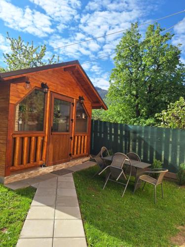 a small cabin with a table and chairs in a yard at Cabana Rustica Georgeta in Zărneşti