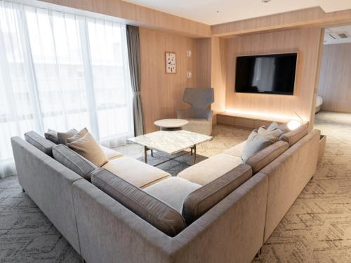 a living room with a large couch and a tv at HOTEL THE LEBEN OSAKA in Osaka