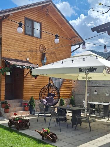 a patio with an umbrella and tables and chairs at Cabana Rustica Georgeta in Zărneşti