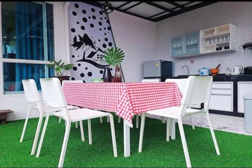 a dining room table with white chairs and a red and white table cloth at Krabi River Cottage Pool Villa in Ban Krabi Yai