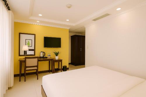 a bedroom with a bed and a desk and a tv at La Bonita - Phu My Hung in Ho Chi Minh City