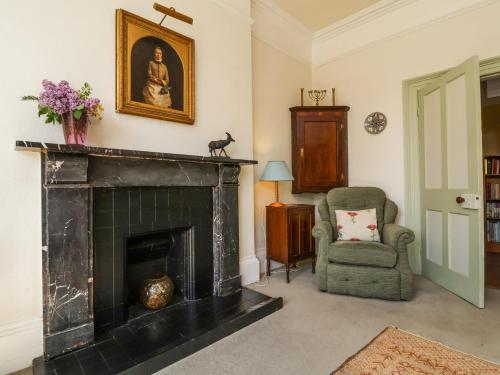 a living room with a fireplace and a chair at The Old Vicarage in Tiverton