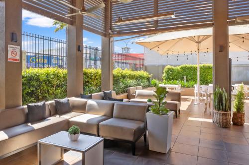 a patio with couches and tables and an umbrella at O'Shea's Royal Hotel in Goondiwindi