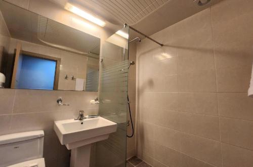 a bathroom with a sink and a shower with a mirror at Jeju BnB Hotel in Jeju