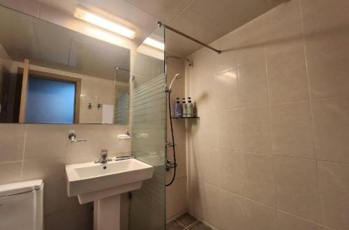 a bathroom with a sink and a shower with a mirror at Jeju BnB Hotel in Jeju