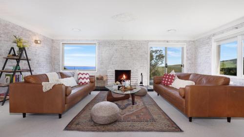 a living room with two brown couches and a fireplace at Halcyon in Kiama