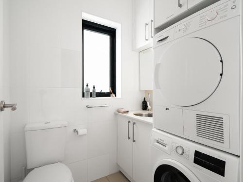 a white bathroom with a sink and a washing machine at The Mitchell Bondi in Sydney