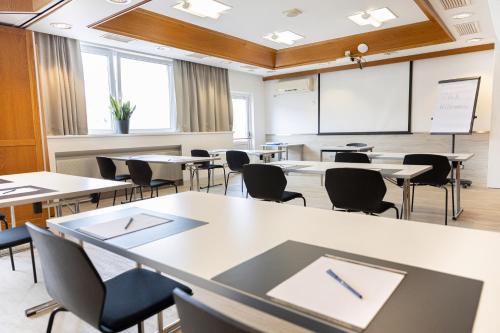 an empty classroom with tables and chairs and a whiteboard at Das Reinisch Hotel - near Vienna Airport in Schwechat
