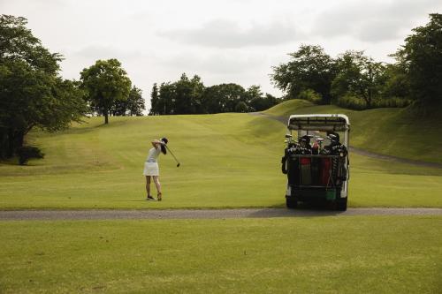 a woman swinging a golf club on a golf course at Hole 37 in Tsukuba