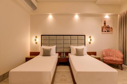a hotel room with two beds and a chair at Lemon Tree Hotel, Mira Road, Mumbai in Sasupāda
