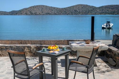 a table with a bowl of fruit on it next to the water at Christine 2 sea view studio WiFi in Elounda