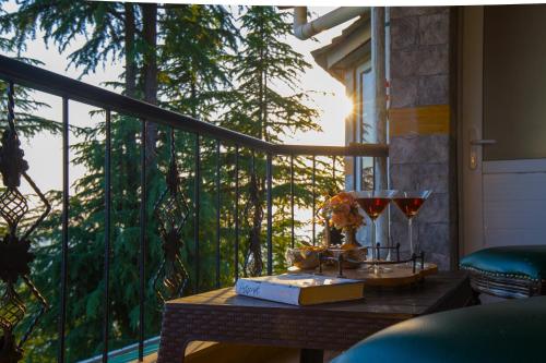 a table on a balcony with a book and a candle at Alaya Stays Hill Top Farmstead Heritage 3 BHK English-Style Villa With Balcony, Gazebo in Nāldera
