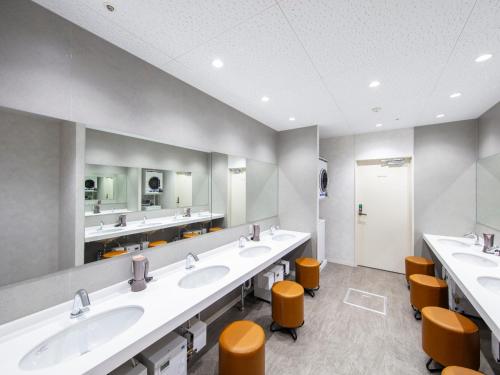 a large bathroom with three sinks and orange stools at STATION INN the URASHIMA in Onomichi