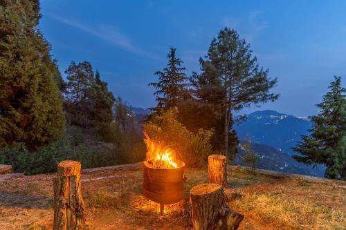 a fire pit in a field with trees and mountains at Alaya Stays Hill Top Farmstead Heritage 3 BHK English-Style Villa With Balcony, Gazebo in Nāldera