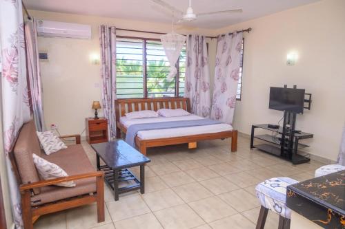 ein Schlafzimmer mit einem Bett, einer Couch und einem Fernseher in der Unterkunft Modern Apartments Nyali in Mombasa