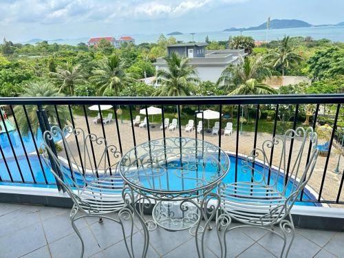 a table and chairs on a balcony with a pool at KEP BAY HOTEL & RESORT in Kep