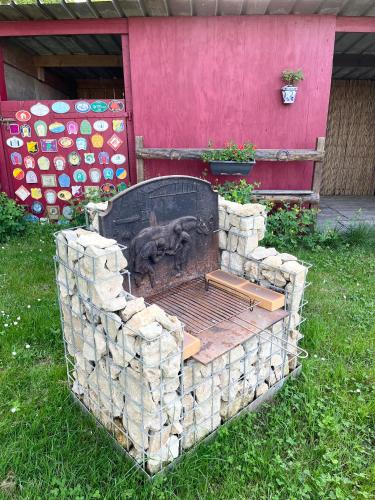 an outdoor grill in the grass in front of a building at Gîte pura vida in Périssac