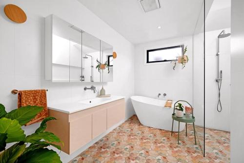 a white bathroom with a tub and a sink at Sandcastle Coastal Retreat in Barwon Heads