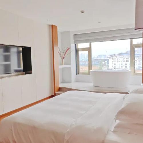 a white bedroom with a large bed and a bath tub at Wingate by Wyndham Libo Center in Libo