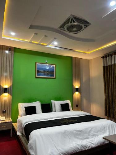 una camera da letto con una parete verde e un letto di Skardu Midway Hotel a Skardu