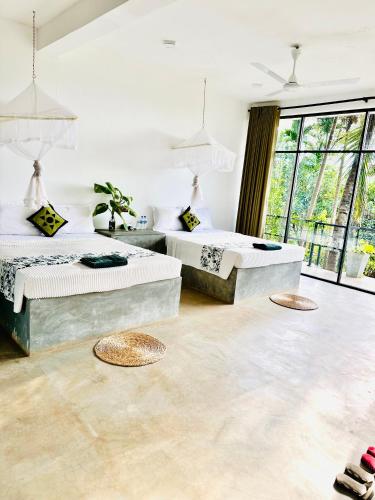 two beds in a white room with windows at Blue Mountains View in Dambulla