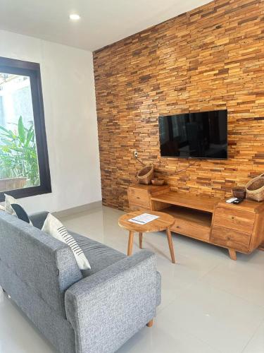 a living room with a couch and a television on a brick wall at 3BR Private Pool Villa Near Dreamland in Uluwatu