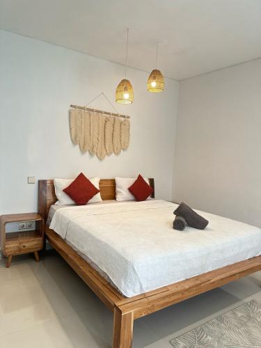 a bedroom with a bed with white sheets and red pillows at 3BR Private Pool Villa Near Dreamland in Uluwatu