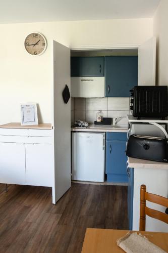 une cuisine avec des placards bleus et blancs et une horloge dans l'établissement Lumineux studio-Gréoux-les-Bains, à Gréoux-les-Bains