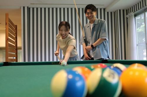 a man and a woman playing a game of pool at Kusatsu Onsen Hotel Village in Kusatsu