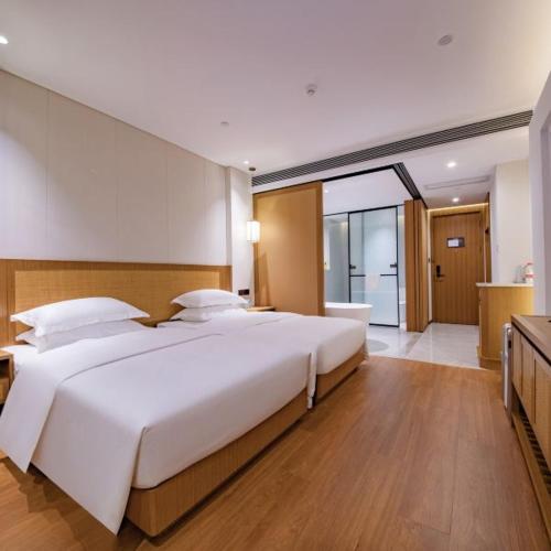 a bedroom with a large white bed and a bathroom at Wingate by Wyndham Libo Center in Libo