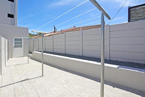 a white fence next to a brick sidewalk next to a building at Apartment 2-bedroom #3 Leetch Views in Cape Town