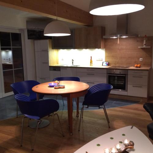 a kitchen with a wooden table and blue chairs at Alpenglück de Luxe Ferienwohnung am Forggensee in Schwangau