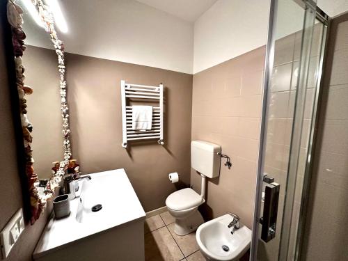 a bathroom with a sink and a toilet and a mirror at Sea la vie Sabbiadoro apartment in Lignano Sabbiadoro