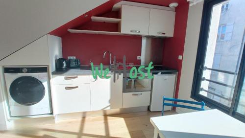 une cuisine avec un lave-linge et un mur rouge dans l'établissement Fonderies Studio Bright Hyper centre, à La Rochelle