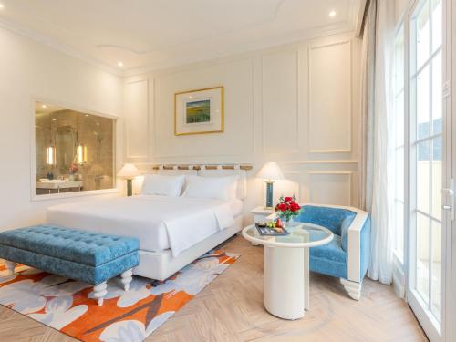 a bedroom with a white bed and a blue stool at Legend Valley Hotel Ha Nam in Phủ Lý