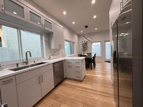 a kitchen with white cabinets and a dining room at Newly constructed 2 bedroom by La Cienega Plaza with parking, modern kitchen, washer dryer and very central to attractions in Los Angeles