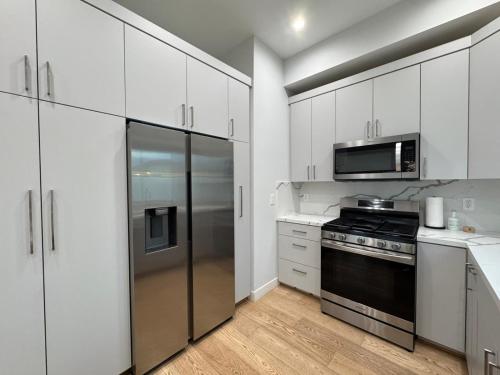 a kitchen with white cabinets and a stainless steel refrigerator at Newly constructed 2 bedroom by La Cienega Plaza with parking, modern kitchen, washer dryer and very central to attractions in Los Angeles