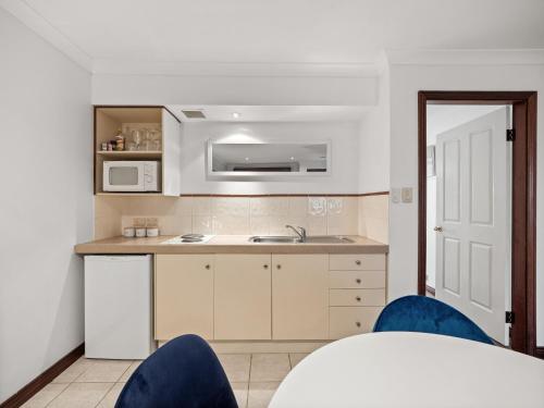 a kitchen with a sink and a counter with blue chairs at Marguerite Studio - central town & pool in Margaret River Town