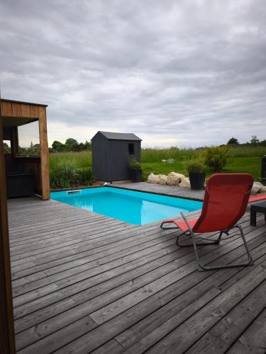 une chaise rouge assise sur une terrasse à côté d'une piscine dans l'établissement Campagne étoilée, à Bellacaud