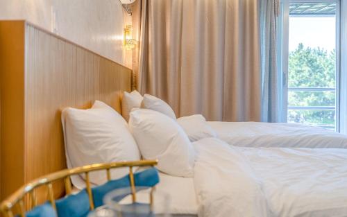 a bedroom with a bed with white pillows and a window at THE OCEAN Pension in Sokcho