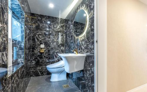 a black tiled bathroom with a toilet and a sink at THE OCEAN Pension in Sokcho