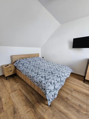 a bedroom with a bed and a wooden floor at Zielony Zakątek in Ramleje