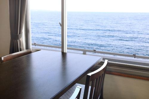 a table and chairs in front of a window with the ocean at Ooedo Onsen Monogatari Beppu Seifu in Beppu