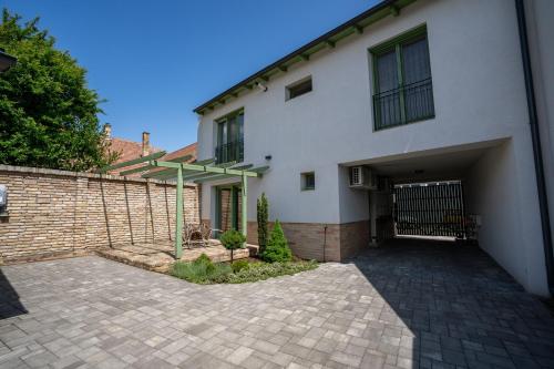 a white house with a garage and a brick wall at Jókai Apartman in Dunaföldvár