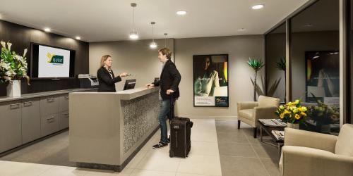 two people standing at a counter in a lobby at Quest Bundoora in Melbourne