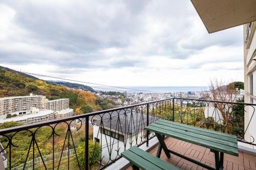 a green bench on a balcony with a view at ITO-SPA Guest House YAMATOSO in Ito