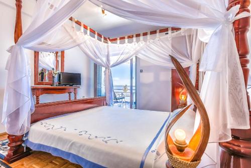 1 dormitorio con cama con dosel y ventana en Villa Roses Apartments & Wellness, en Ičići