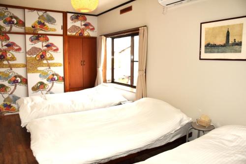 two beds in a room with a window at Traditional Japanese House -in Matsumoto Asama Onsen- in Matsumoto
