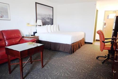 a hotel room with a bed and a red couch at Days Inn by Wyndham Taber in Taber