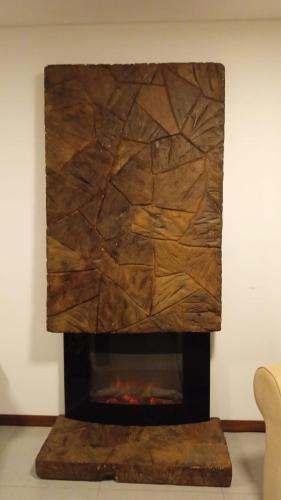 a fireplace in a living room with a stone wall at Cazartes in Treinta y Tres